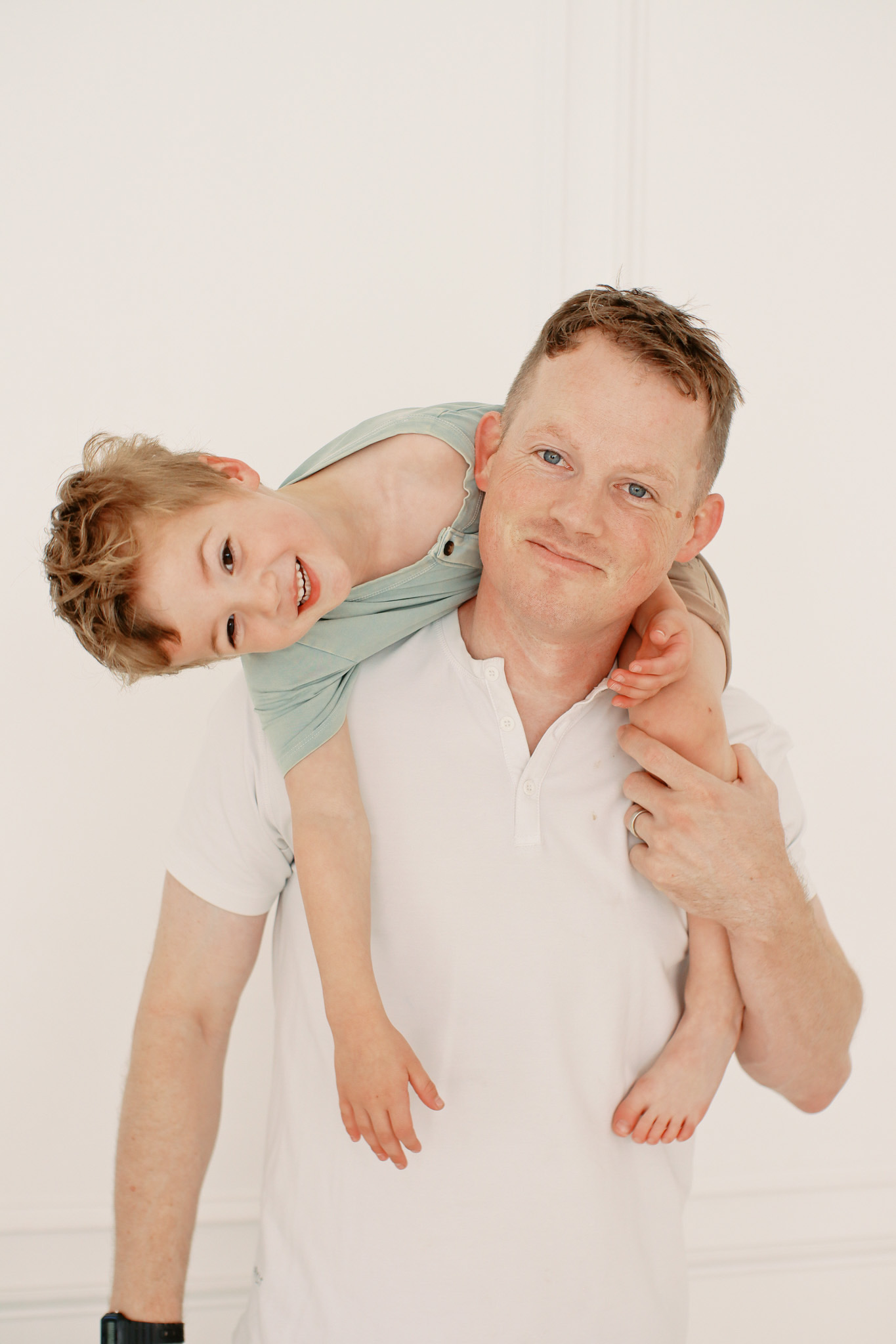 a father holding his toddler son over his shoulder