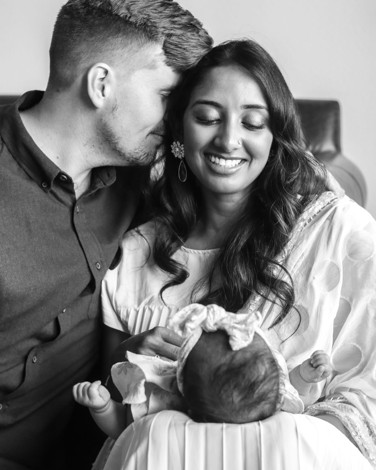 a black and white photo of a husband and wife holding their newborn
