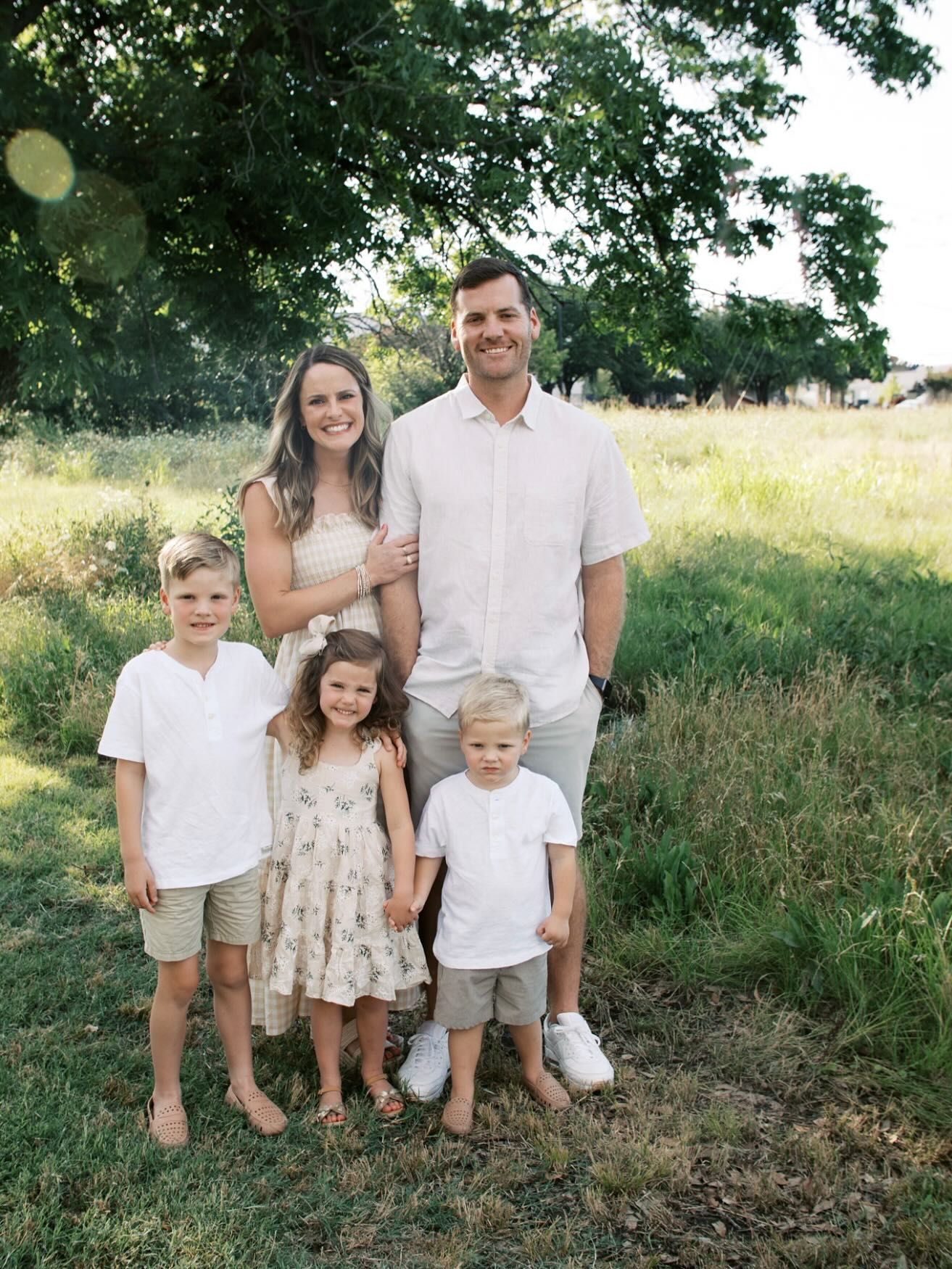 a family of 5 under a tree in a field of tall grass